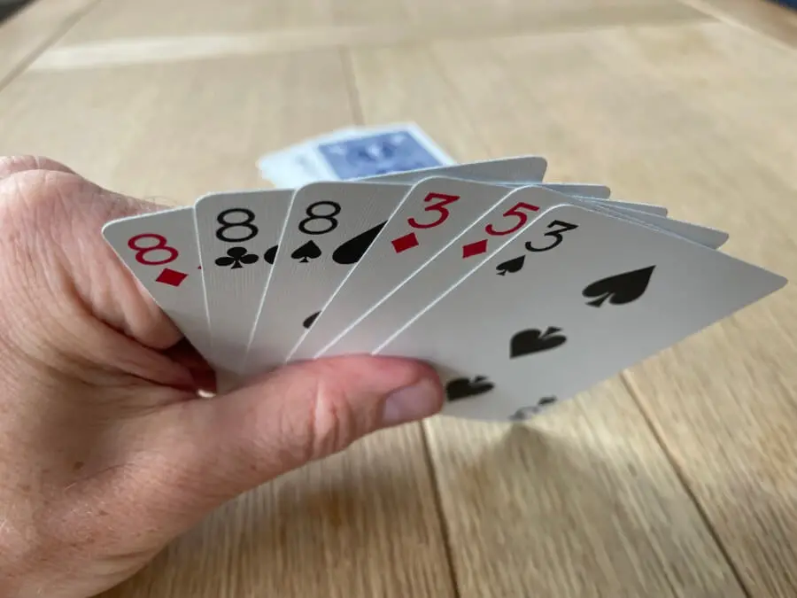 A hand of six cards showing three 8's, two 3's and a 5