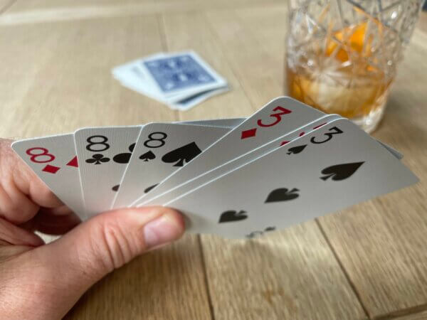 A hand of six cards showing three 8's, two 3's and a 5, with the 3's and 5 about to be used