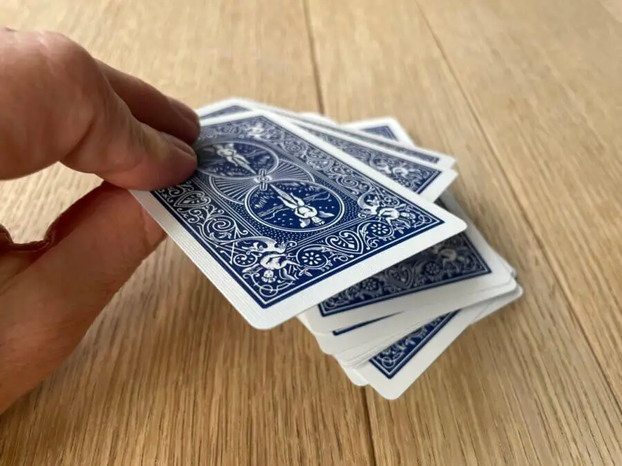Three playing cards being placed face-down on top of a deck of cards