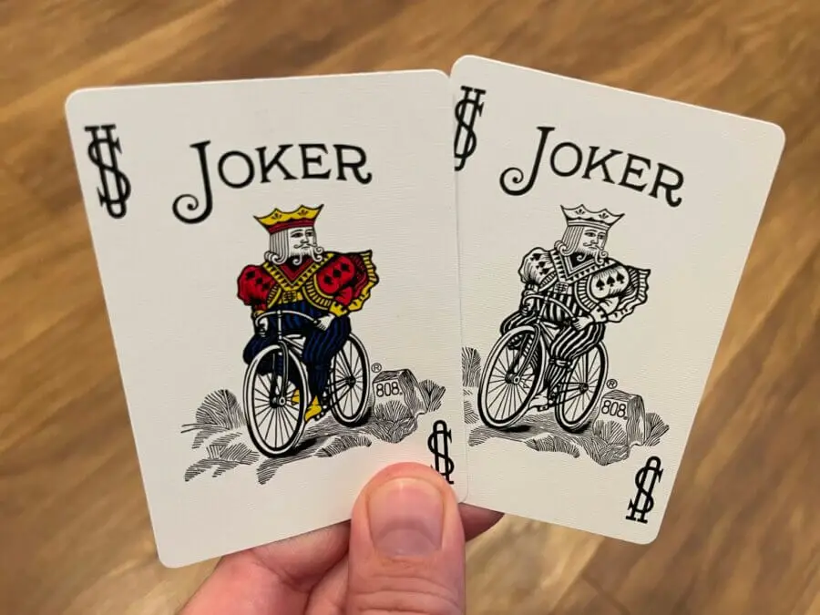 A pair of Jokers held up against a blurred wooden background