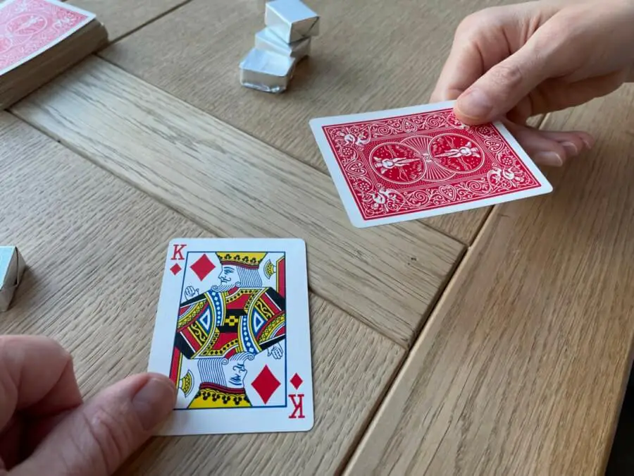 A player revealing a King of Diamonds in the game Chase The Ace
